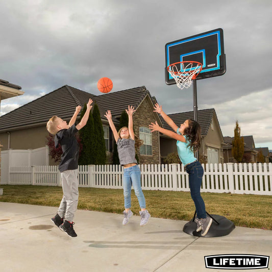 Side angle view of the Lifetime 32 inch youth portable basketball hoop featuring a high-density polyethylene backboard set up on an outdoor driveway.