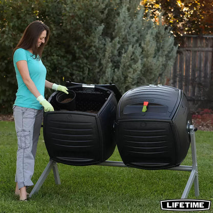 A side-by-side view of the Lifetime 378L dual tumbling composter on a sturdy steel base, situated on a clean garden patio, showing the black panels and red processing indicators.