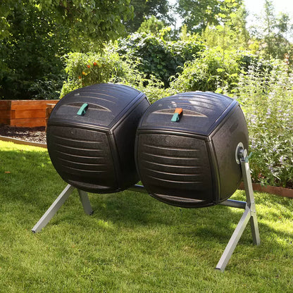 A side-by-side view of the Lifetime 378L dual tumbling composter on a sturdy steel base, situated on a clean garden patio, showing the black panels and red processing indicators.