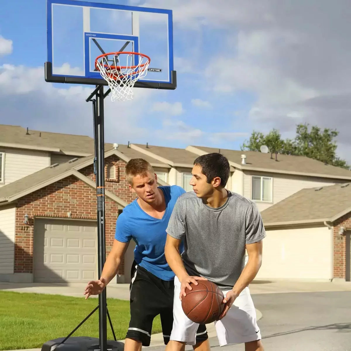 Black and red Lifetime 48 inch portable basketball hoop with clear shatter-proof backboard set up on a paved outdoor driveway.