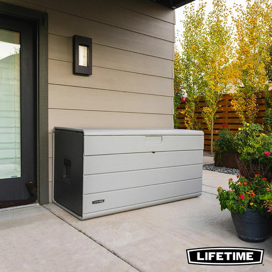 Lifetime 984L extra-large outdoor deck box in neutral tones, featuring a sturdy lid and internal divider on a garden patio.