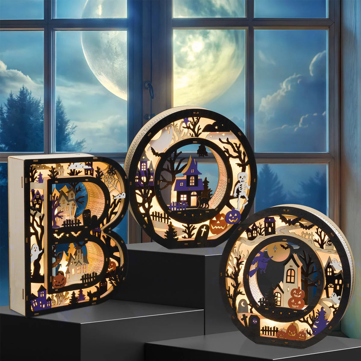 Set of three large illuminated wooden BOO letters featuring detailed laser-cut Halloween scenes emitting a warm LED glow on a dark wooden mantle shelf.