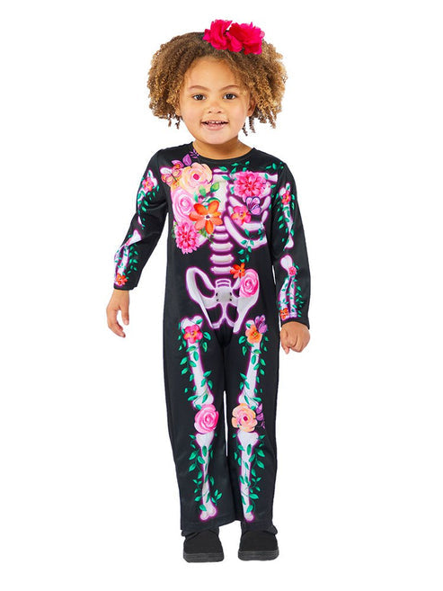 Toddler wearing a black Little Floral Skeleton jumpsuit with colorful flower print bone designs against a neutral backdrop.
