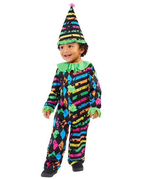 A child wearing a spooky Little Funhouse Clown jumpsuit and matching pointed clown hat standing in a Halloween setting.