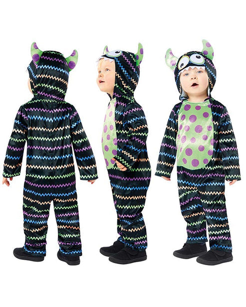 Front view of a child wearing a soft blue and orange Little Monster Costume jumpsuit with an attached character face hood in a cozy living room setting.