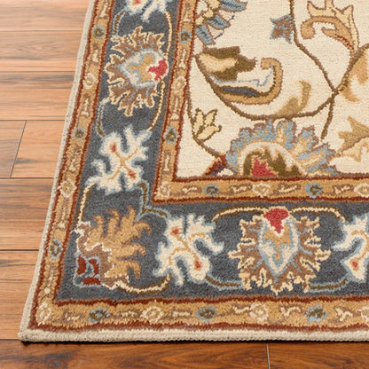 Top-down angle showing the detailed cream and muted floral pattern of the hand-tufted Livabliss Caesar wool rug styled on light oak flooring under a wooden coffee table.