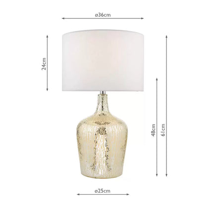 A Lolek silver glass table lamp with a glowing, textured mercury finish base and an ivory faux silk drum shade illuminating a cozy bedside table environment.