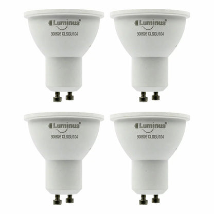 Four white Luminus Smart GU10 LED spotlight bulbs arranged neatly on a dark wooden countertop casting a soft multi-coloured glow.
