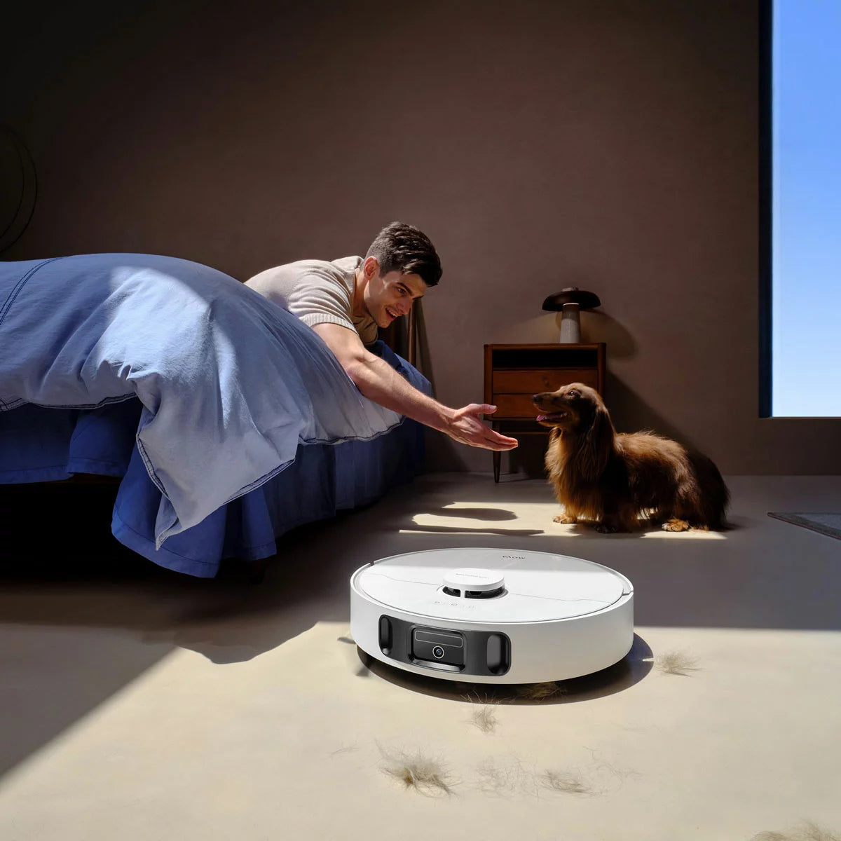 Top-down view of the sleek white MOVA E30 Ultra Robot Vacuum docking into its tall auto-empty cleaning station on light hardwood flooring.