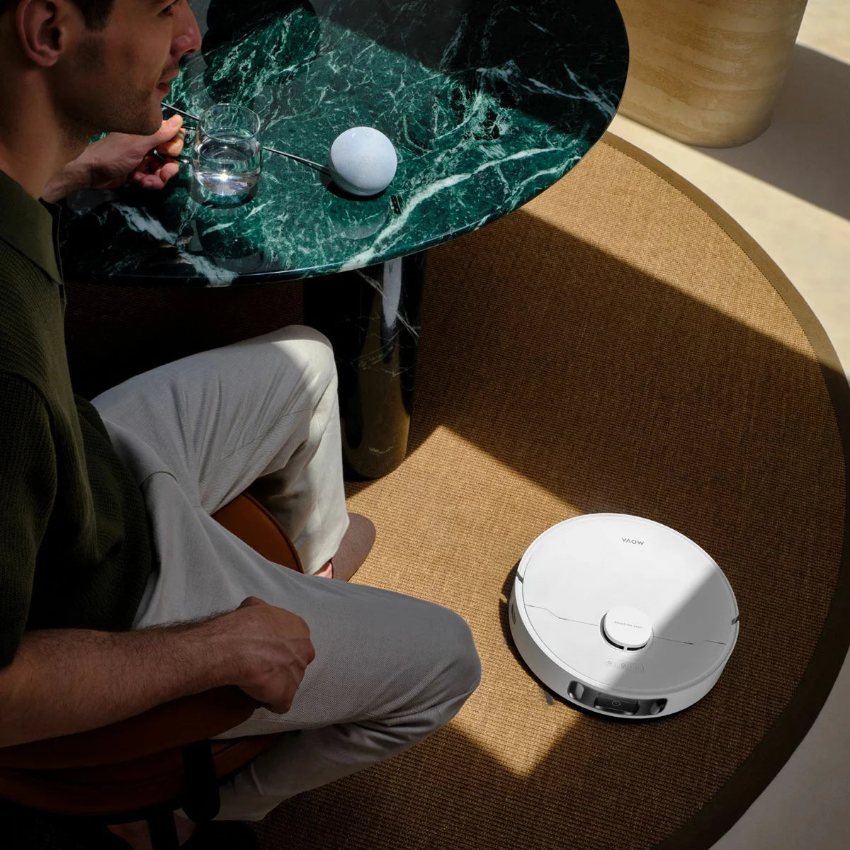 Top-down view of the sleek white MOVA E30 Ultra Robot Vacuum docking into its tall auto-empty cleaning station on light hardwood flooring.