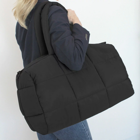 Front angle view of the soft MYTAGALONGS Cloud Duffle Weekender Bag showing its plush quilted polyester texture, top handles, and adjustable shoulder strap.