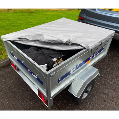 A silver galvanised steel Maypole SY120 utility trailer with its grey weather-resistant PVC flat cover tied down tightly with elasticated cords, viewed from a three-quarter angle.