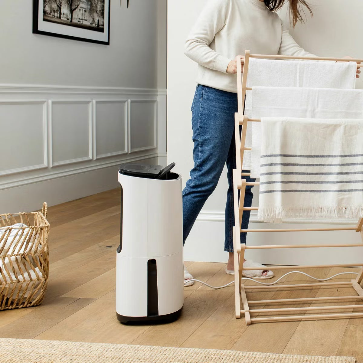 MeacoDry Arete Two 25L Dehumidifier and Air Purifier in charcoal finish with digital LCD display standing on dark hardwood flooring in a spacious living room.
