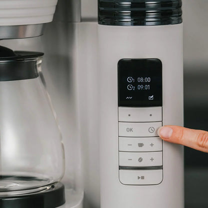 Side profile of the black and stainless steel Melitta AromaFresh Grind & Brew coffee machine with a glass carafe set on a clean kitchen countertop.