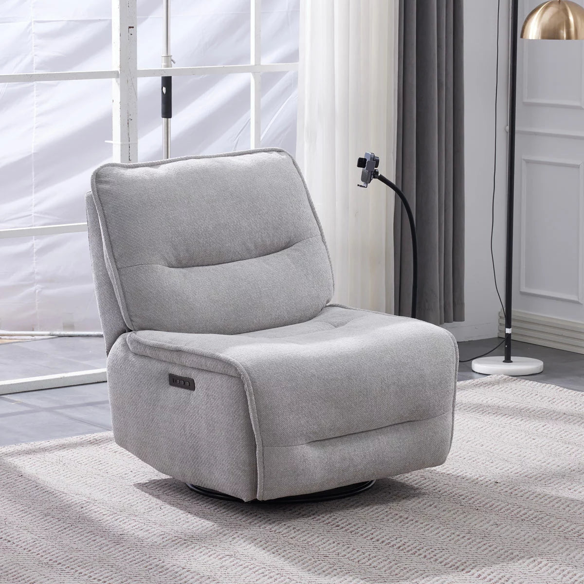 Front three-quarter angle of the Meteor grey fabric power reclining swivel chair, highlighting its plush textured weave, modern armrests, adjustable wireless charging phone cradle, and metallic swivel base.