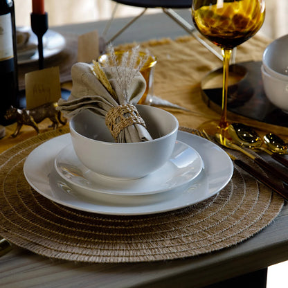 The Mikasa Alexis 12-Piece Porcelain Dinnerware Set neatly arranged on a table, highlighting its clean white finish and modern coupe-style plates and bowls.
