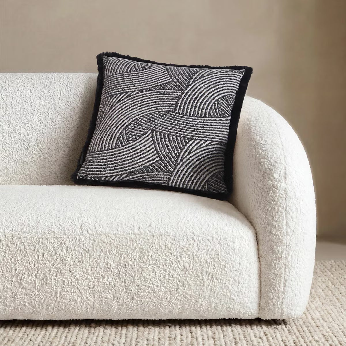 Front view of the 50x50 cm Mon Chateau tweed cushion resting on a sofa, showing its patterned fabric front alongside the plush faux fur edge.