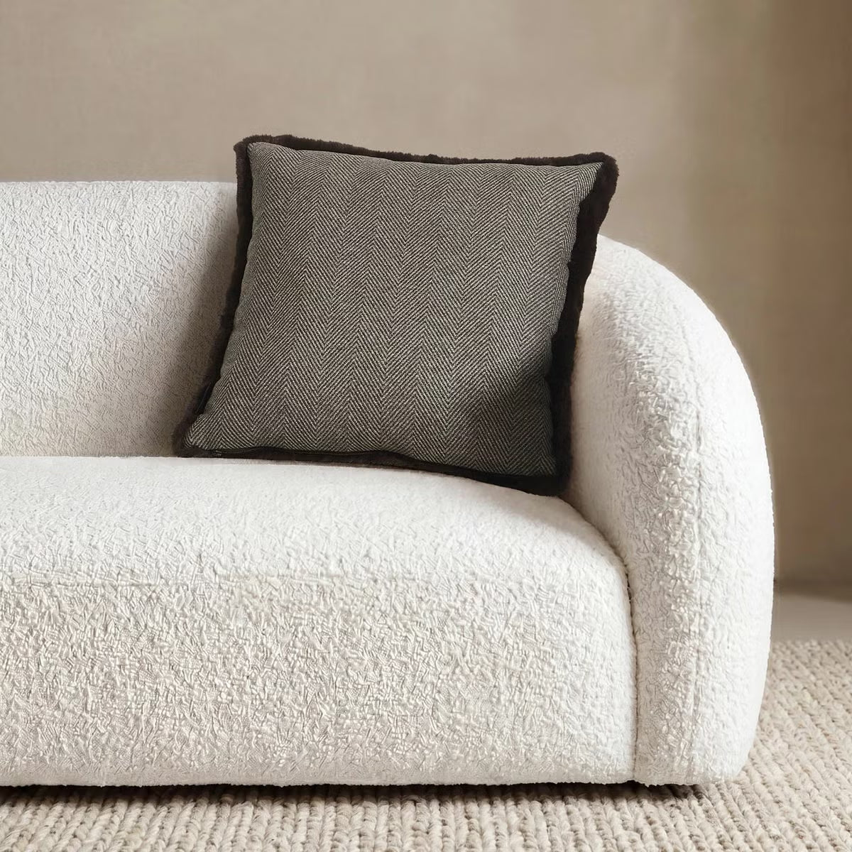 Front view of the 50x50 cm Mon Chateau tweed cushion resting on a sofa, showing its patterned fabric front alongside the plush faux fur edge.