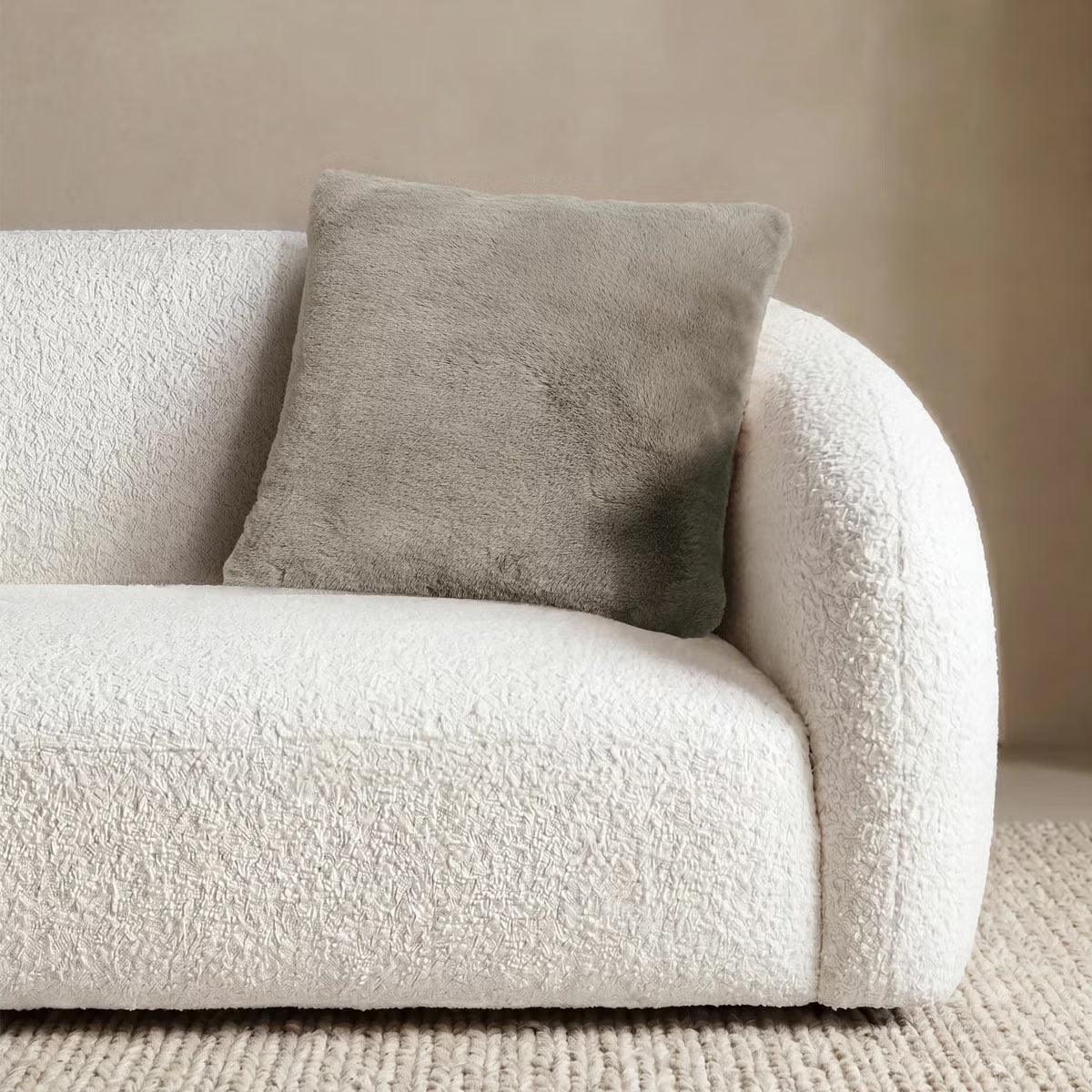 Front view of the 50x50 cm Mon Chateau tweed cushion resting on a sofa, showing its patterned fabric front alongside the plush faux fur edge.