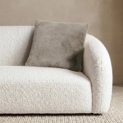 Front view of the 50x50 cm Mon Chateau tweed cushion resting on a sofa, showing its patterned fabric front alongside the plush faux fur edge.