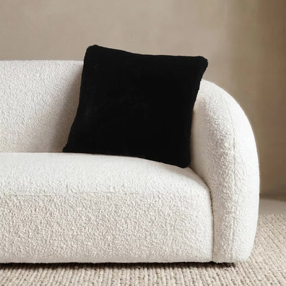 Front view of the 50x50 cm Mon Chateau tweed cushion resting on a sofa, showing its patterned fabric front alongside the plush faux fur edge.