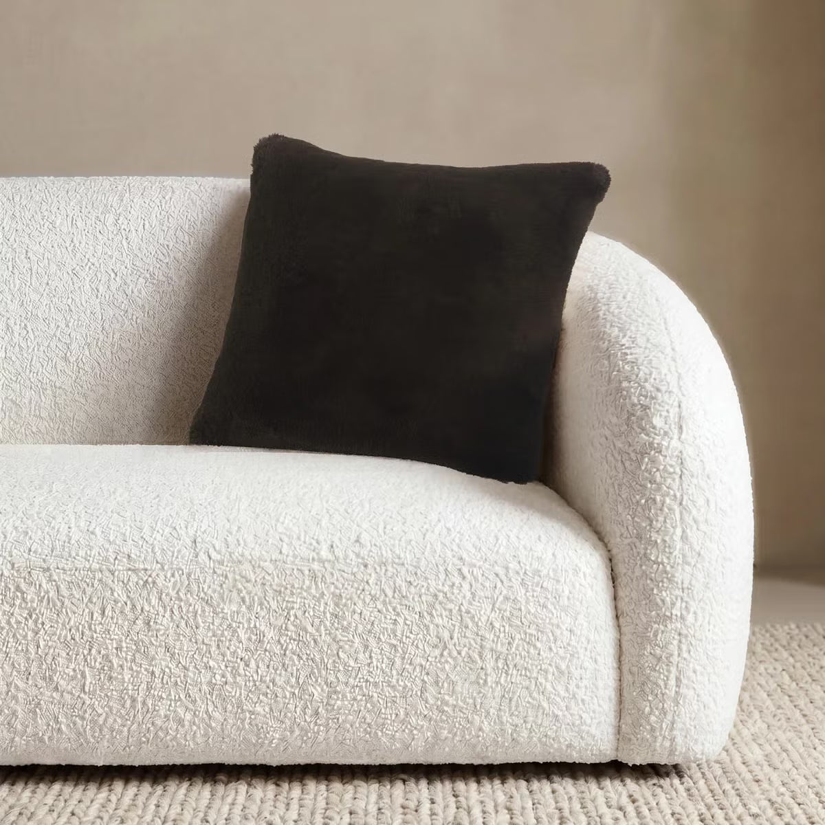 Front view of the 50x50 cm Mon Chateau tweed cushion resting on a sofa, showing its patterned fabric front alongside the plush faux fur edge.