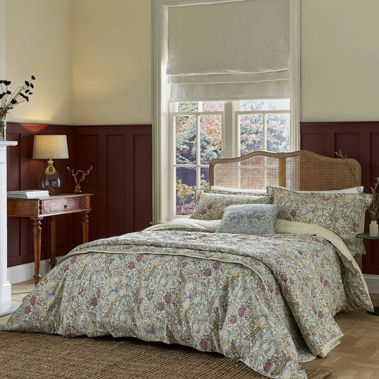 A styled bedroom scene displaying the Morris & Co. Golden Lily duvet cover set on a king size bed, showcasing the intricate green and yellow botanical tendrils and matching Oxford pillowcases.