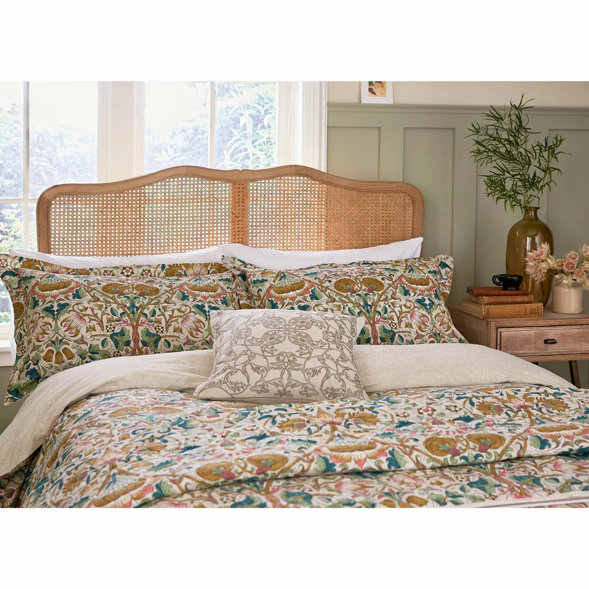 A wide angled shot of the Morris and Co Lodden Primrose duvet cover set outspread on a master bed highlighting the detailed interlocking yellow and beige floral patterns.