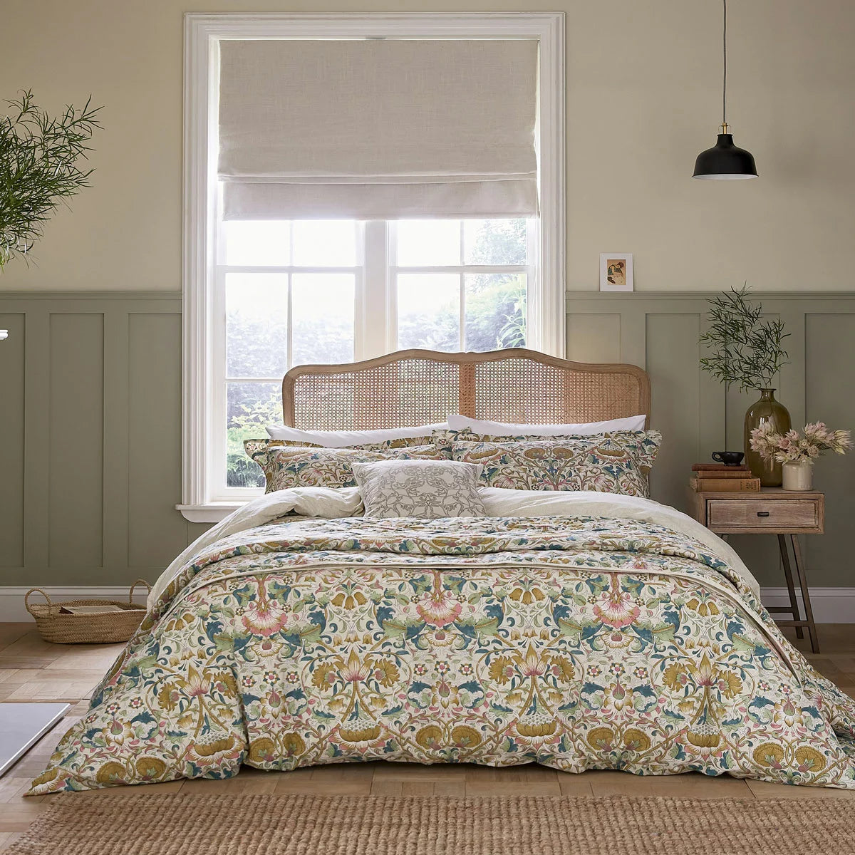 A wide angled shot of the Morris and Co Lodden Primrose duvet cover set outspread on a master bed highlighting the detailed interlocking yellow and beige floral patterns.