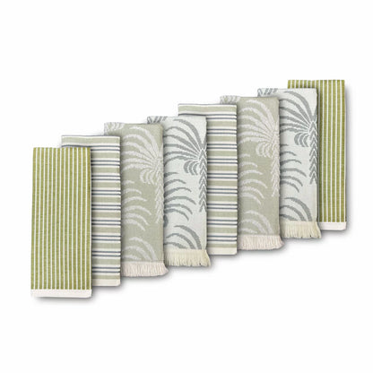 A stack of Mundo Textile kitchen towels in blue, red, neutral, and green patterns on a wooden kitchen surface.