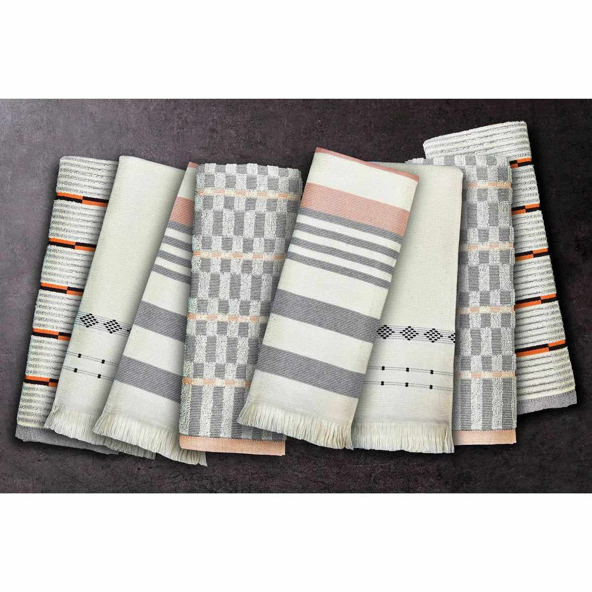 A stack of Mundo Textile kitchen towels in blue, red, neutral, and green patterns on a wooden kitchen surface.