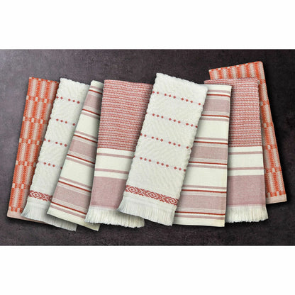 A stack of Mundo Textile kitchen towels in blue, red, neutral, and green patterns on a wooden kitchen surface.