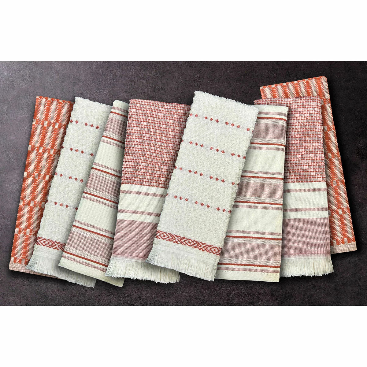 A stack of Mundo Textile kitchen towels in blue, red, neutral, and green patterns on a wooden kitchen surface.
