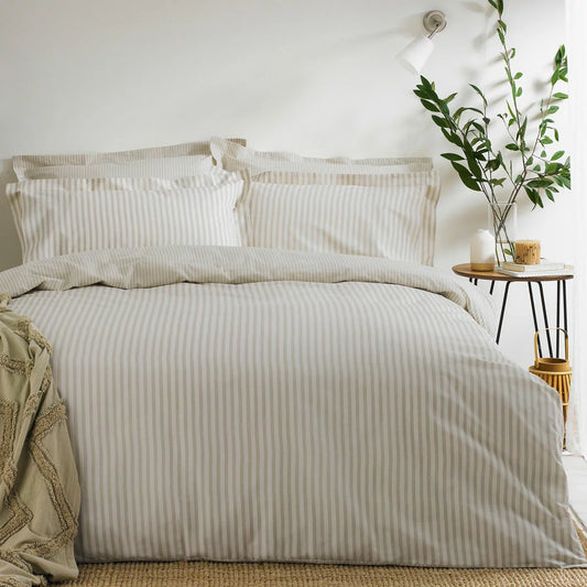 A single bed styled with the Yard Hebden cotton natural stripe duvet cover set, showcasing the soft cream and sand-colored patterns in a bright, modern minimalist room.