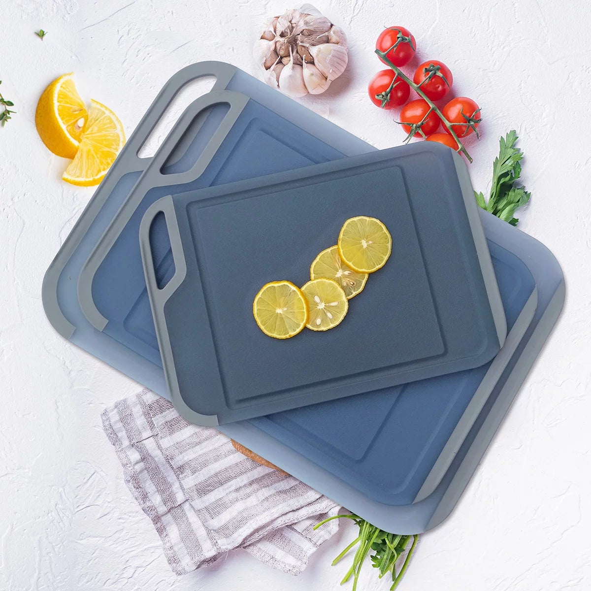 Three color-coded Neoflam cutting boards with non-slip handles and juice grooves stacked neatly on a white quartz kitchen countertop.