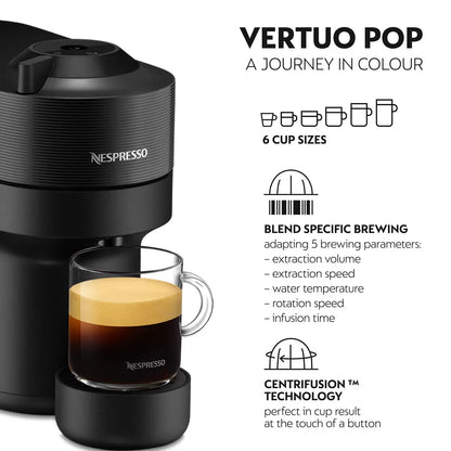 Front view of the matte black De'Longhi Nespresso Vertuo Pop coffee machine on a kitchen counter with a glass mug filled with layered coffee and rich foam.