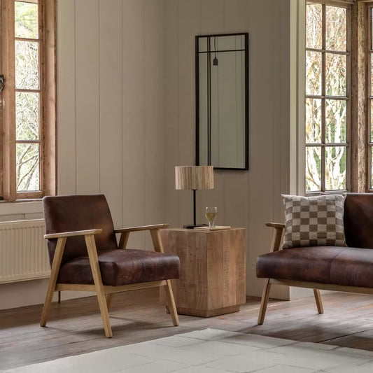 A side angle view of the Gallery Neyland brown leather armchair highlighting its rich top grain upholstery and smooth solid wood frame in a bright room.