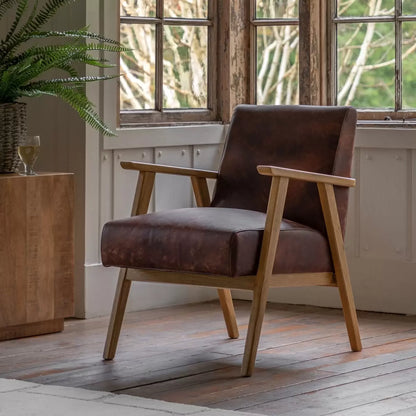 A side angle view of the Gallery Neyland brown leather armchair highlighting its rich top grain upholstery and smooth solid wood frame in a bright room.