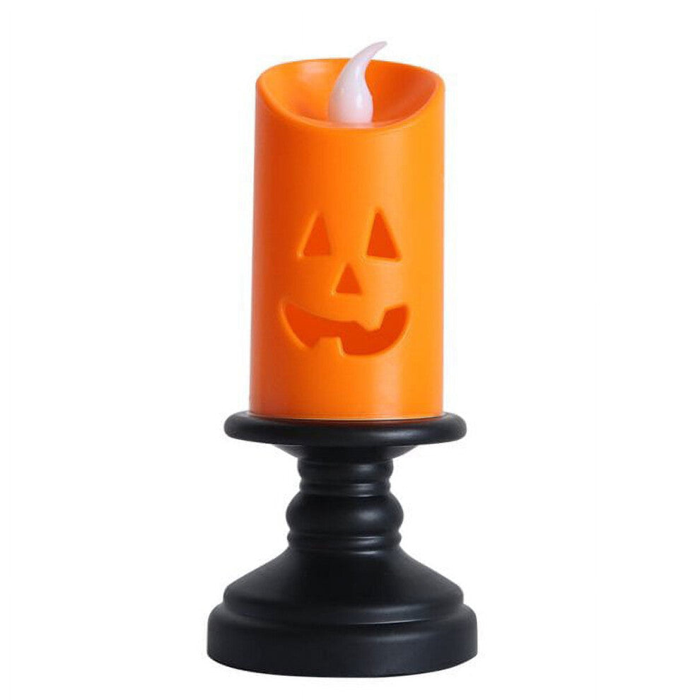 A Nightwill LED pumpkin candle light with a hollow ghost face design glowing softly on a festive party table.