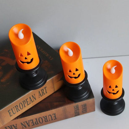 A Nightwill LED pumpkin candle light with a hollow ghost face design glowing softly on a festive party table.