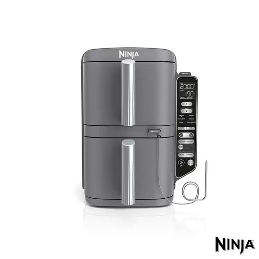 Front angle view of the black and stainless steel Ninja Double Stack 9.5L SL451UK Air Fryer sitting under kitchen cabinets with both drawers open showing wire racks and crisping layers.