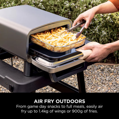 Front view of the grey Ninja MO203UK electric outdoor pizza oven with glowing interior light displaying a fresh 12-inch artisan pizza on the stone.
