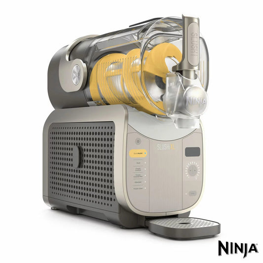 Front angle view of the mocha Ninja FS601UKBR SLUSHi XL Frozen Drink Maker sitting on a kitchen counter with a filled clear vessel and anti-drip pour spout.