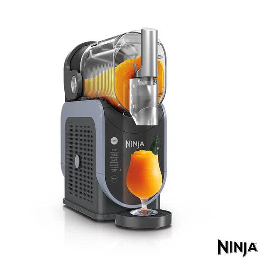 Front view of the grey Ninja Slushi Frozen Drink Maker FS301UK on a modern kitchen countertop dispensing a colorful frozen slush cocktail from its easy-pour handle.