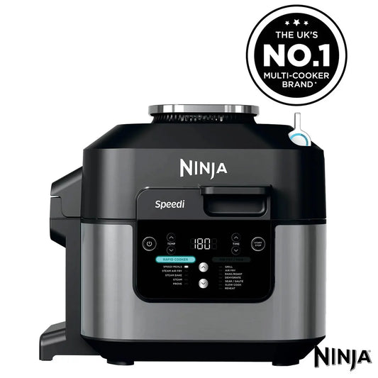 Front view of the black steel Ninja Speedi ON500UK multi cooker sitting on a dark kitchen countertop with its lid open, displaying cooked chicken breasts and steamed vegetables inside the inner pot.