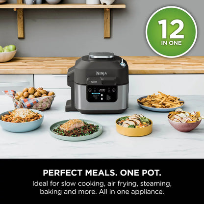 Front view of the black steel Ninja Speedi ON500UK multi cooker sitting on a dark kitchen countertop with its lid open, displaying cooked chicken breasts and steamed vegetables inside the inner pot.