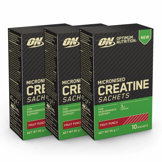 Three boxes of Optimum Nutrition Creatine Monohydrate Fruit Punch sachets displayed alongside an individual single-serve packet on a kitchen counter.