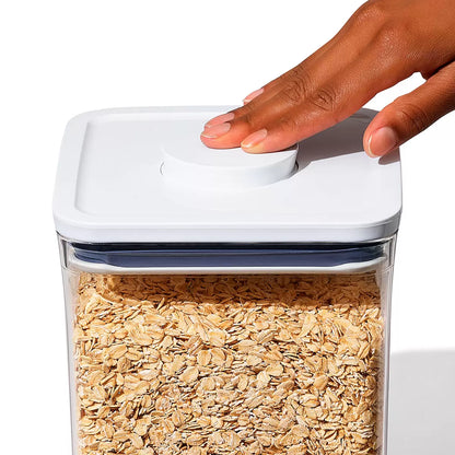 The OXO SoftWorks 8-Piece POP Container Set arranged on a shelf, showcasing transparent stackable canisters with push-button lids in various sizes.