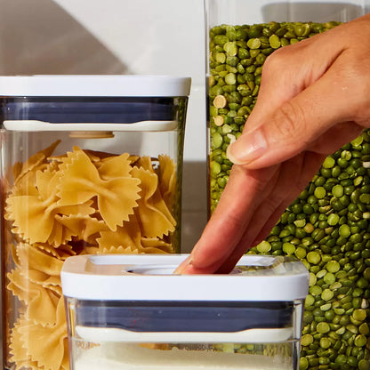 The OXO SoftWorks 8-Piece POP Container Set arranged on a shelf, showcasing transparent stackable canisters with push-button lids in various sizes.