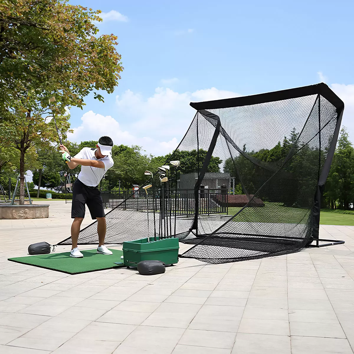 Front three-quarter view of the large black On Par Deluxe Home Golf Driving Net set up on a green garden lawn with its wide side protection wings fully extended.